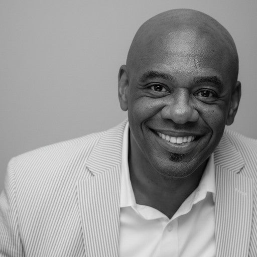 Smiling bald man in a light-colored striped blazer and white shirt, looking at the camera.